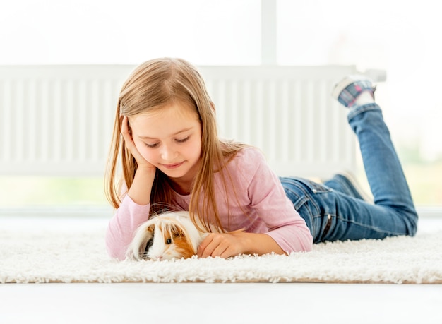 Chica sujetando el conejillo de Indias en el piso