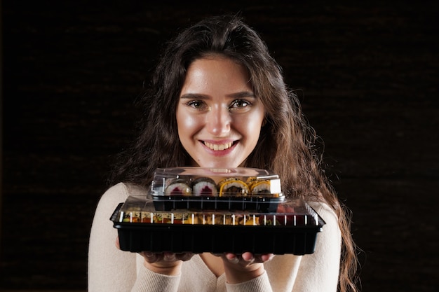 Chica sujetando dos cajas de sushi sobre fondo negro