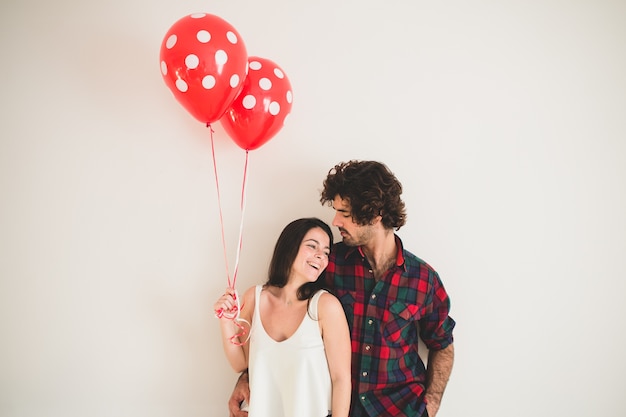 Foto chica sujetando dos globos con su novio al lado