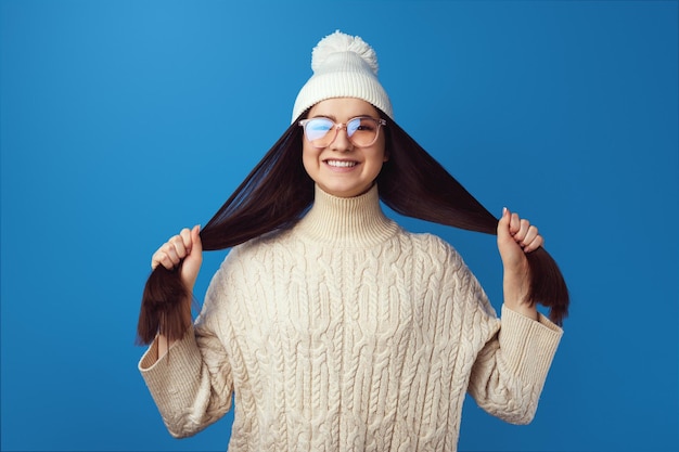 Chica sujetando el pelo chica feliz y divertida aislada sobre fondo azul.