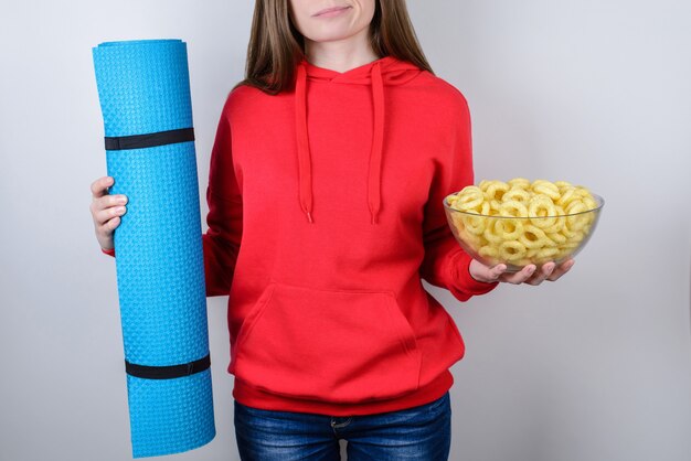 Chica sujetando el plato con comida y estera de deportes azul aislado fondo gris