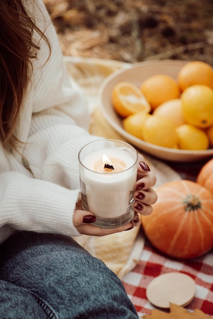 Chica sujetando velas aromáticas sentado en plaid