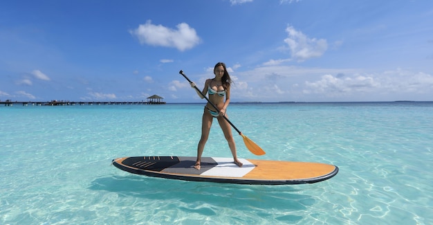 Chica de SUP surf en Maldivas