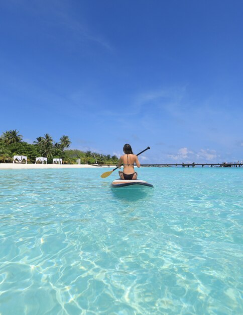 Chica de SUP surf en Maldivas