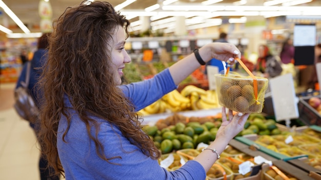 Chica en supermercado selecciona kiwi