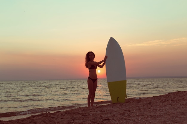 Chica surfista en la playa al atardecer