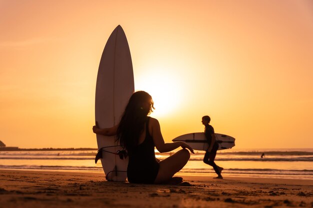 Chica surfista de silueta en la playa al atardecer