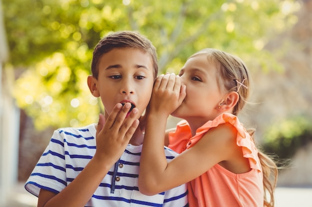 Chica susurrando un secreto al oído del niño