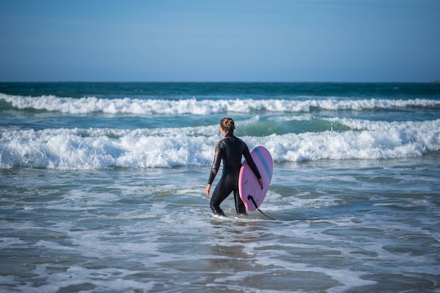 Foto chica con una tabla de surf supera las olas. concepto: superación, determinación, belleza increíble