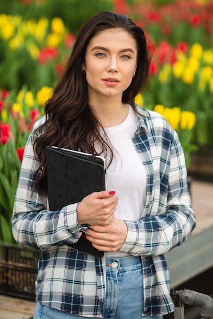 Chica con tablet trabajador con flores en invernadero Concepto de trabajo en las flores de invernadero