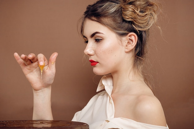 Chica con tarro de miel. Concepto de comida sana, dieta, postre. hermosa niña sonríe y toca la miel con las manos sobre la mesa