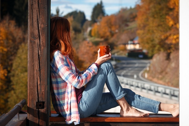 Chica con una taza de café. imagen tomada a través del cristal de una ventana. mañana al amanecer