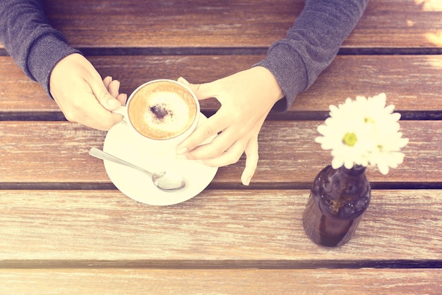 Chica con una taza de café en la mesa de madera