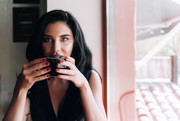 Chica con una taza de capuchino en un café