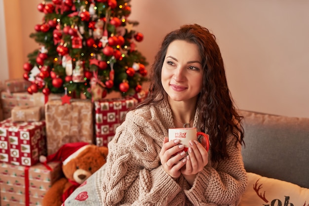 Chica con una taza de malvavisco en el interior de Año Nuevo en casa