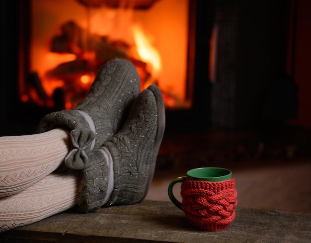 Chica en taza de zapatillas en madera vintage junto a la chimenea