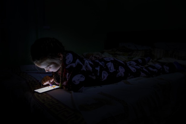 Una chica con un teléfono móvil en la cama.