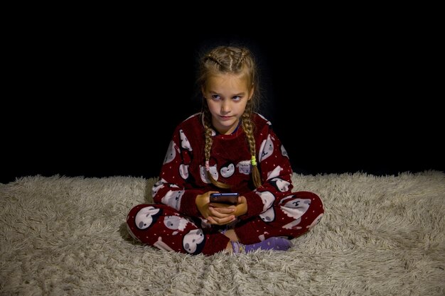 Una chica con un teléfono móvil en la cama.