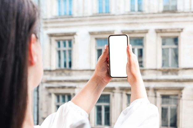 Chica con un teléfono con una pantalla en las manos contra el fondo de un edificio antiguo