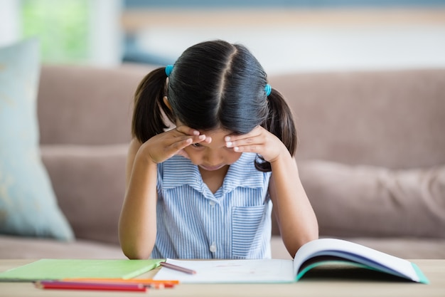 Chica tensa haciendo su tarea en la sala de estar