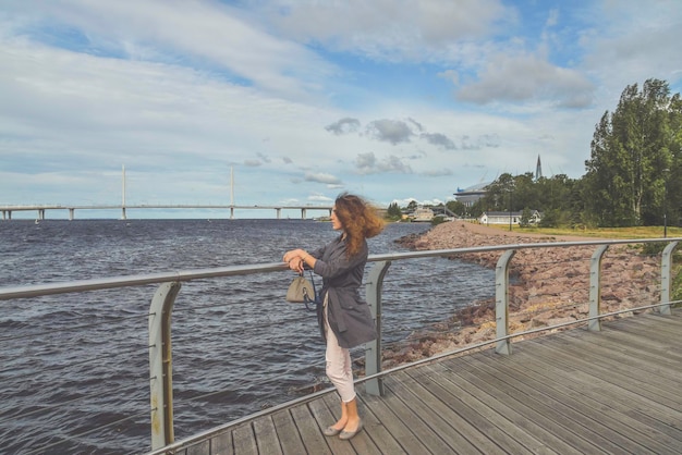 La chica en el terraplén mira a lo lejos hacia el mar.