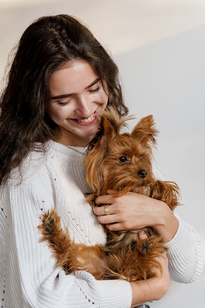 Chica tiene perro marrón aislado en la pared blanca