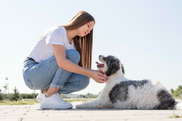 Foto chica de tiro completo mirando lindo perro