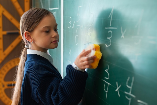 Foto chica de tiro medio aprendiendo matemáticas en la escuela.