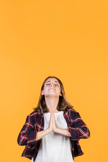 La chica de tiro medio da la posición de oración.