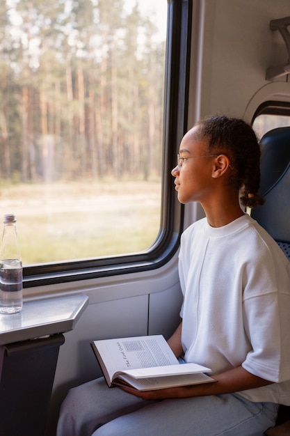 Foto chica de tiro medio con libro en tren.