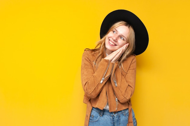 Chica tocada en ropa de moda de otoño sobre fondo amarillo aislado una mujer mira el espacio de la copia