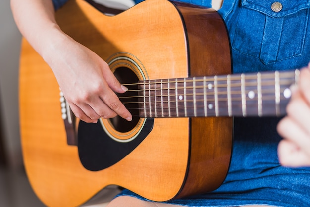 Chica tocando el aislante de guitarra acústica en blanco