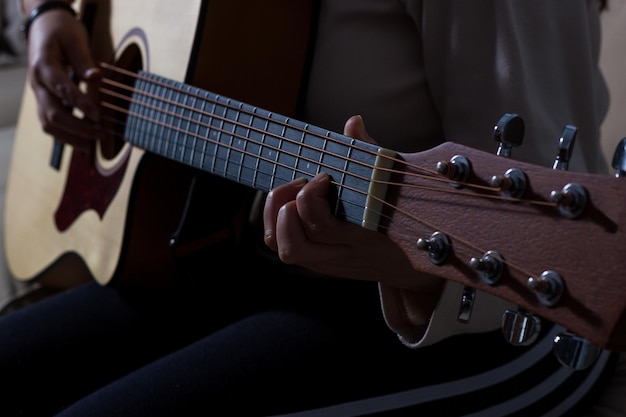 Chica tocando una guitarra acústica en un ambiente relajado.