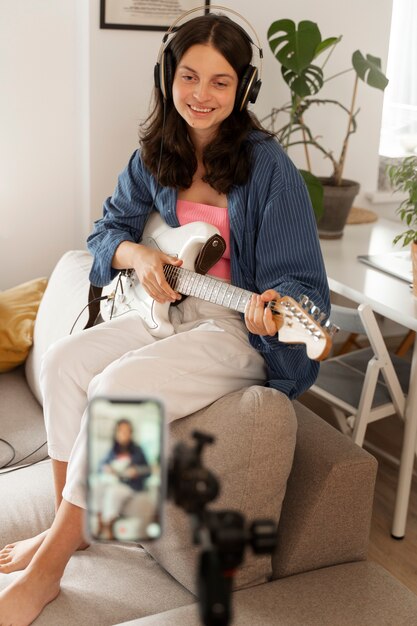 Foto chica tocando la guitarra en casa tiro completo