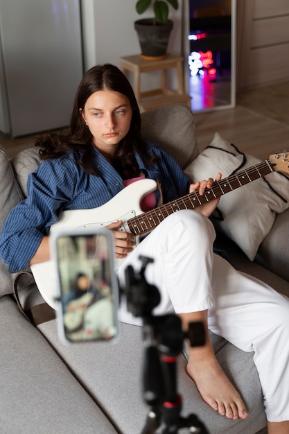 Foto chica tocando la guitarra en el interior tiro completo