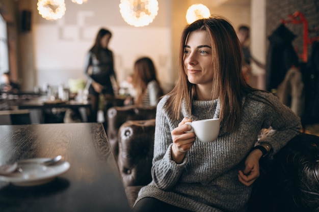 Chica tomando café en una cafetería en invierno