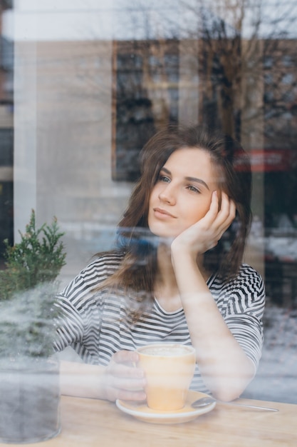 Chica tomando café en una cafetería.