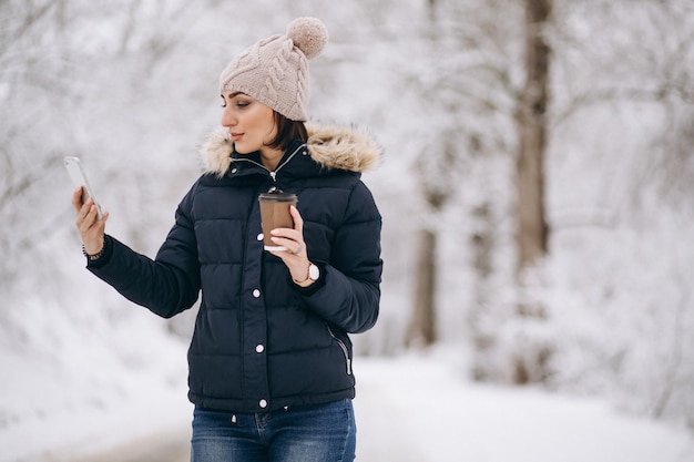 Chica tomando café y hablando por teléfono afuera en invierno