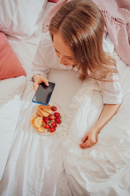 Chica tomando foto de plato con vista superior de fresas