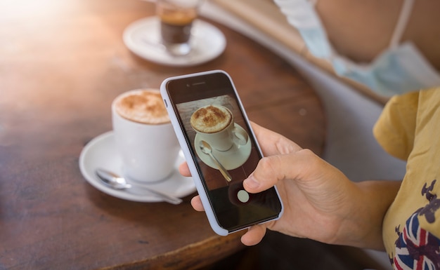 Chica tomando foto de una taza de café