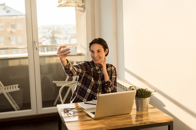 Foto chica tomando selfie de la oficina en casa mientras toma un descanso del proyecto