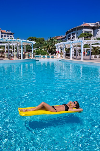 Chica tomando el sol en la piscina