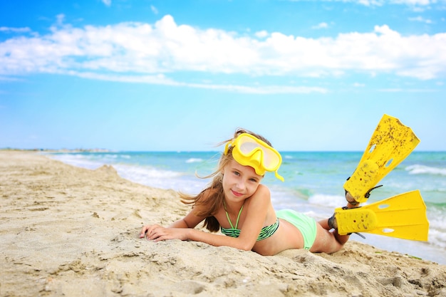 Chica tomando el sol en la playa con máscara y aletas para bucear.