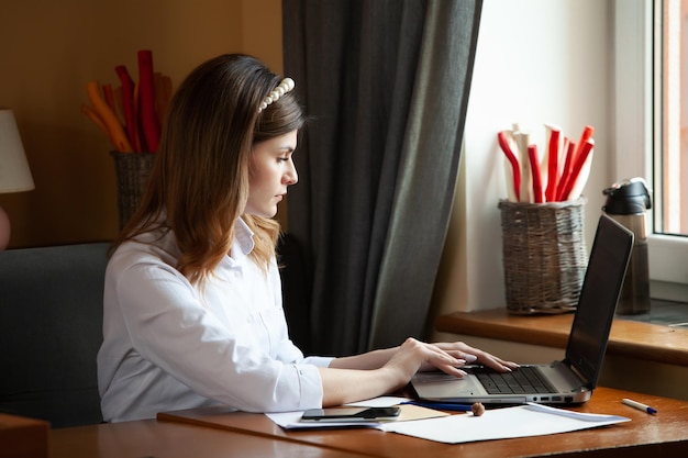 La chica trabaja en la computadora en un café Estudiante de aprendizaje en línea Blogger