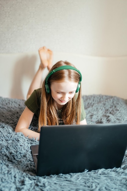 la chica trabaja en la computadora portátil con auriculares en la cama