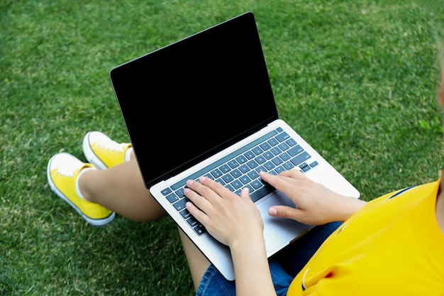 Una chica trabaja en una computadora portátil en el césped