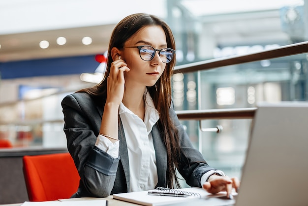 Chica trabaja en una computadora portátil en el lugar de trabajo. Mujer de negocios exitosa crea una startup y toma decisiones.