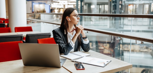 Chica trabaja en una computadora portátil en el lugar de trabajo. Mujer de negocios exitosa crea una startup y toma decisiones.