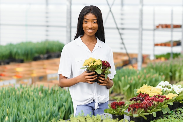 Chica, trabajadora con flores en invernadero