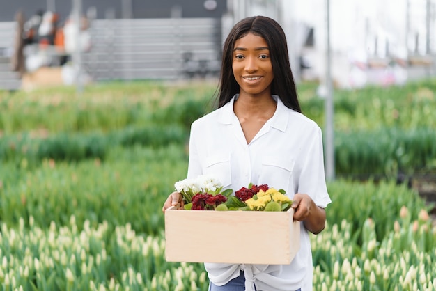 Chica, trabajadora con flores en invernadero